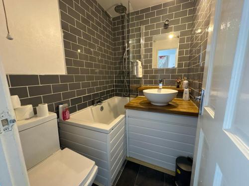 a bathroom with a sink and a tub and a toilet at The Cozy Hideaway - 2 Bedroom apartment with garden in Orpington with free Parking in Foots Cray