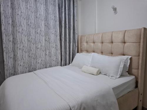 ナイロビにあるNGT Luxury homesの寝室にある白いシーツと枕が置かれたベッド