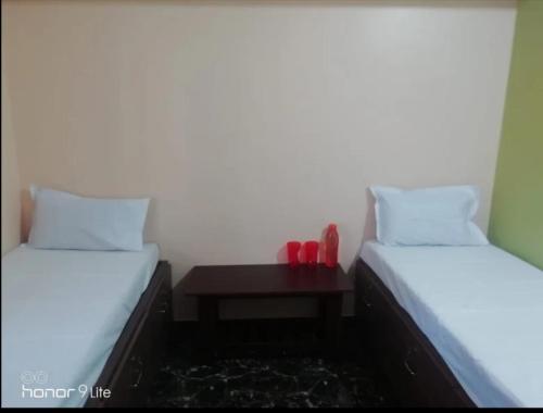 two beds with red shoes on a table in a room at BLU mango PG & HOME STAY in Mysore
