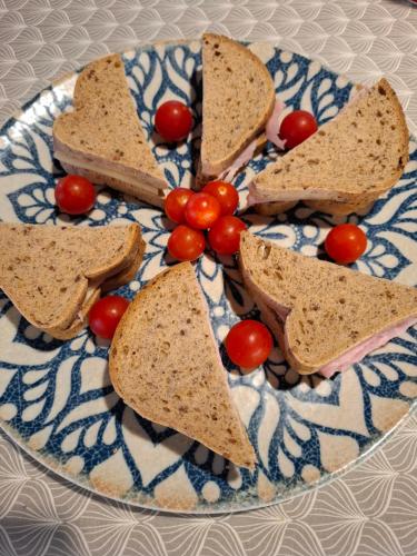 a plate with four sandwiches and tomatoes on it at Podere Radici - Room & Breakfast in Misano Adriatico