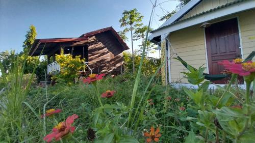 a garden with flowers in front of a house at Don Som Riverside Guesthouse in Don Som