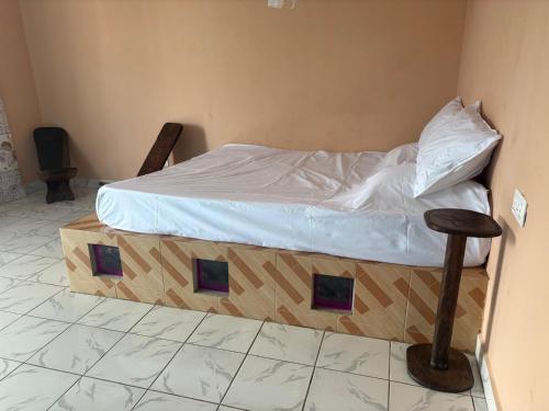 a bedroom with a bed with white sheets and a stool at Jusula Beach Humble Abode in Sanyang