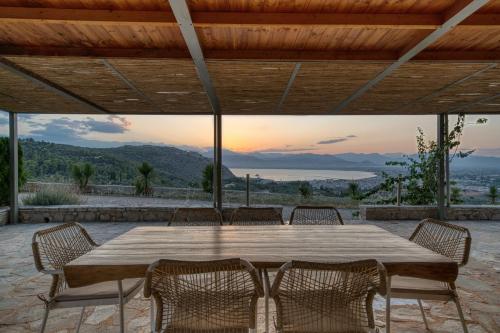een grote houten tafel met stoelen op een patio bij Finca Nafplio Hills, spectacular sea view in Nafplio