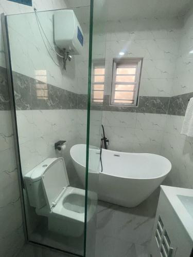 a bathroom with a toilet and a sink and a tub at Essence Apartments in Ikeja