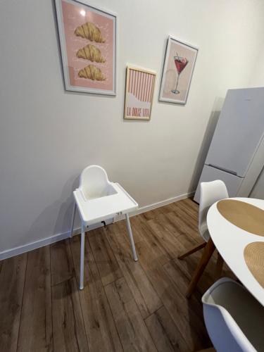 a room with a white table and chairs and paintings at Central Terrace Apartment in Nové Zámky
