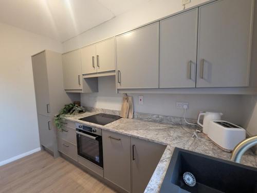 a kitchen with white cabinets and a sink at Modern 1-Bed Tandragee Portadown - BT62 2BP in Tandragee