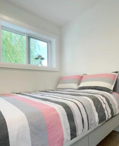a bedroom with a bed with a striped blanket at A Beautiful, cozy second floor room for staying in Vancouver