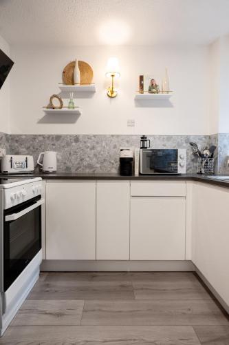 a white kitchen with white cabinets and appliances at Finnieston 1BR - Walk to Hydro & SEC - Parking in Glasgow