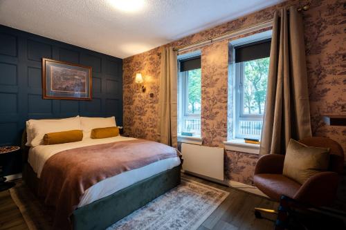 a bedroom with a bed and a chair and windows at Finnieston 1BR - Walk to Hydro & SEC - Parking in Glasgow