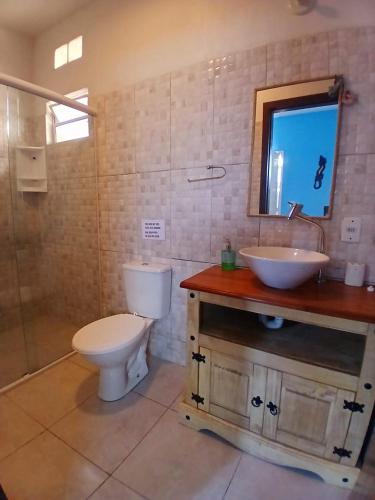 a bathroom with a toilet and a sink and a mirror at Solar del Mar in Praia do Rosa