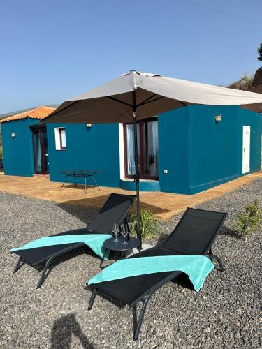 two chairs and an umbrella in front of a house at Casa Noroeste in Puntagorda