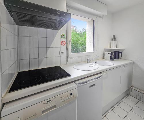 een witte keuken met een spoelbak en een fornuis bij Horizon sérénité - in Deauville