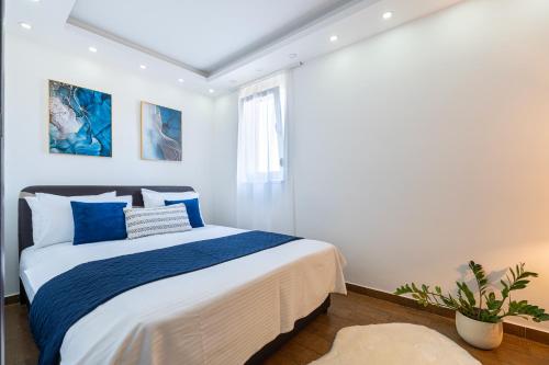 a white bedroom with a bed with blue pillows at BlueMont Apartment in Podgorica