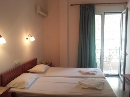 ルトラ・エディプソスにあるDimitra Hotelのベッドルーム1室(ベッド2台付)、スライド式ガラスドアが備わります。