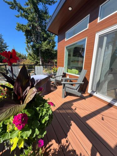 a deck with a bench and flowers on a house at Serene Forest Retreat in Sooke