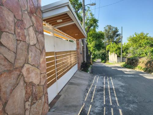 a building with a stone wall next to a road at Casa Marcy, casa nueva con alberca y tres recamaras in Pazulco