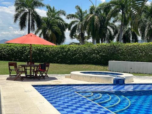 a table and umbrella next to a swimming pool at Villa familiar con piscina y jacuzzi privado in Tocaima