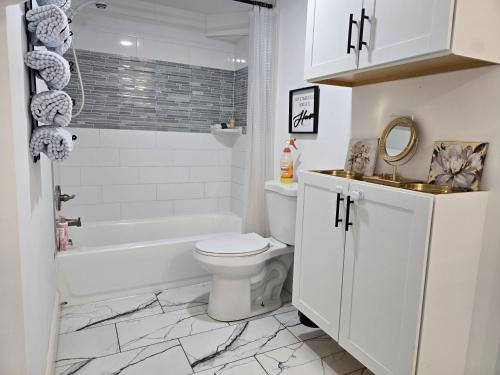 a bathroom with a toilet and a tub and a sink at Winston Ardmore Executive King Bed Suite &hot tub in Winston-Salem