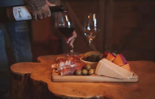 a plate of food on a table with a glass of wine at Boutique Flat com Banheira Lareira e Piscina Aquecida in Campos do Jordão