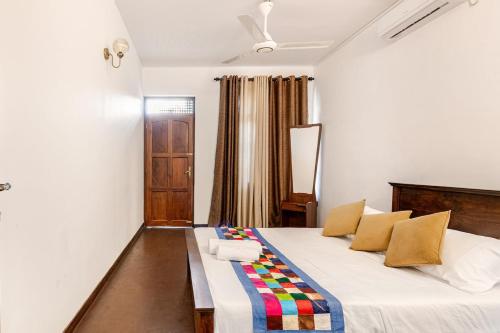 a bedroom with a large white bed with colorful pillows at The Samdro Colombo in Colombo