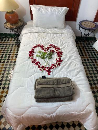 a white bed with a heart made out of flowers at Riad Iman in Fès