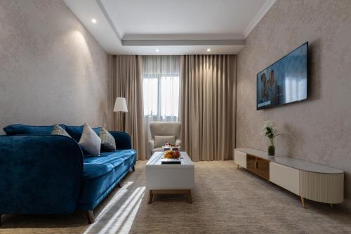 a living room with a blue couch and a table at Lumian Hotel in Al Madinah