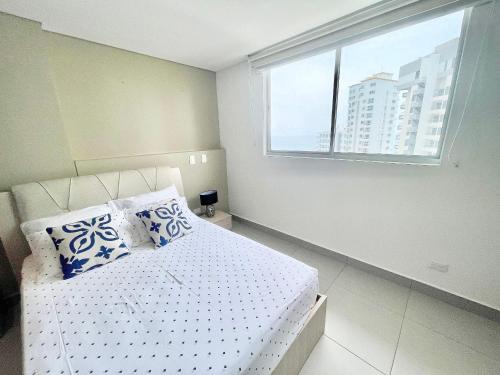 a bedroom with a white bed with pillows and a window at Ámbar Roca / Rodadero in Rodadero