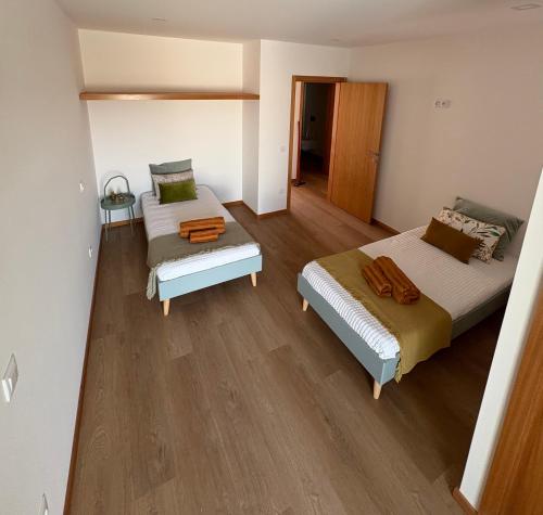 two beds in a room with wooden floors at Casa do Rio in Aguçadoura