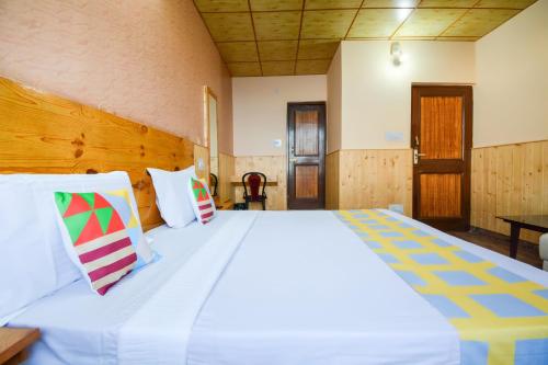 a bedroom with a large white bed with colorful pillows at Hotel O Krishna Monal Delightful Stay in Shimla