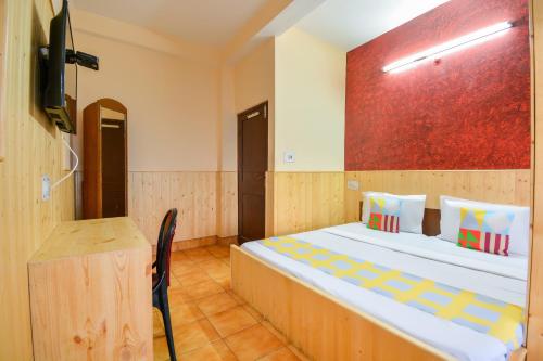 a bedroom with a bed and a tv and a desk at Hotel O Krishna Monal Delightful Stay in Shimla