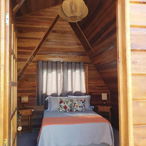 a bedroom with a bed in a wooden house at Chalé Nina in Areias