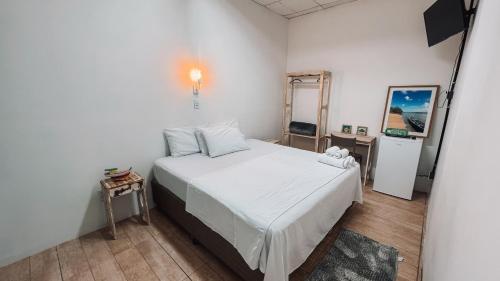 a bedroom with a white bed and a mirror at Grand'Hostel in São Cristóvão