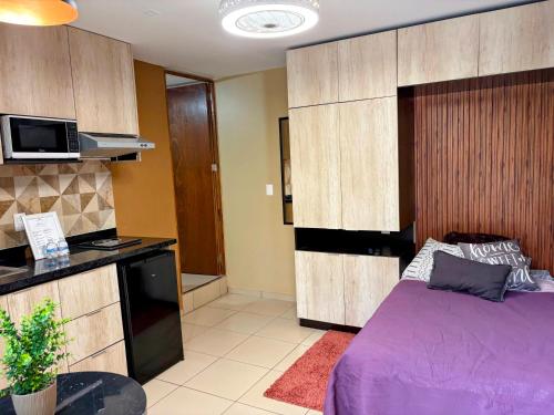 a bedroom with a purple bed and a kitchen at 05 Habitación tranquila a pasos de Ceconexpo in Morelia
