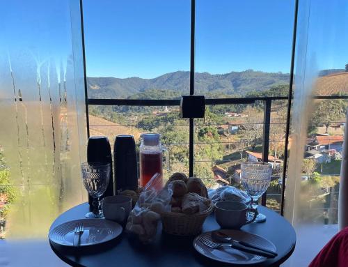 a table with plates and wine glasses and a view at Chalé Garden da Mantiqueira in Monte Verde