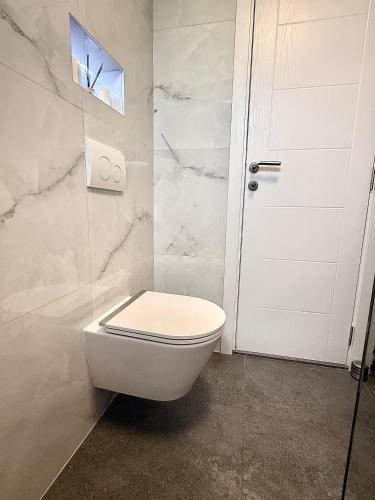 a bathroom with a white toilet and a door at Apartments Oriens 7 in Zagreb