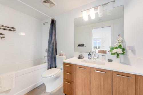 a bathroom with a sink and a toilet and a bath tub at Luxury 2-Bedroom Condo with Floor-to-Ceiling Windows and City Views in Vancouver