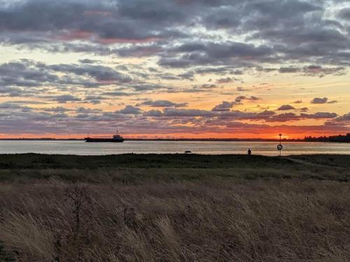 a sunset on the beach with a ship in the water at Charming Harbor Cottage-By Traum in Jægerspris