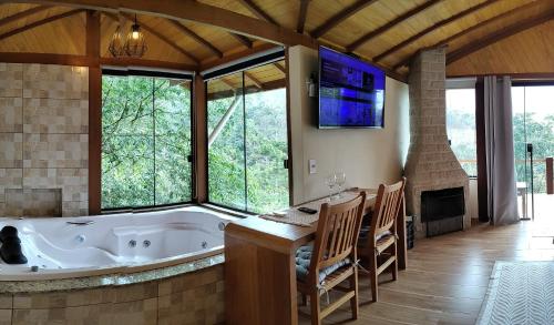 a large bathroom with a tub and a table and chairs at pousada caminho do escorrega in Visconde De Maua
