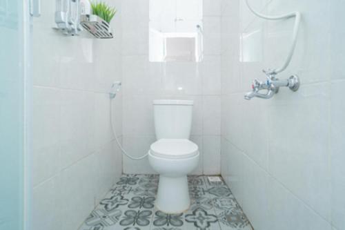 a white bathroom with a toilet and a shower at Sazara Hotel Batu in Selecta