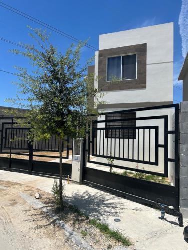 a house with a black and white fence and a tree at Casa Elite in Monterrey