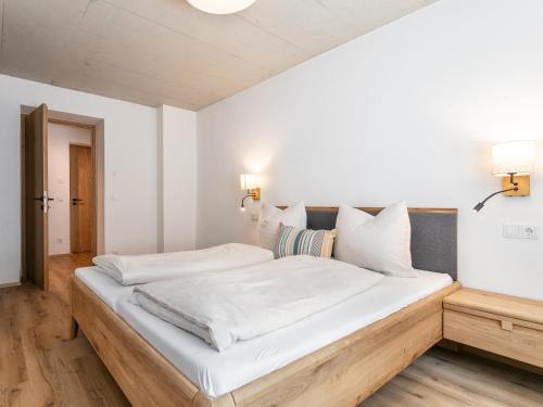 a bedroom with a large bed with white sheets at Hopfgarten Alpin Living Top 6 in Hopfgarten im Brixental