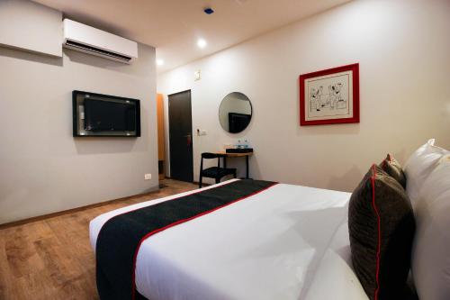 a hotel room with a bed and a tv at Super Townhouse RCC Elite in Hyderabad