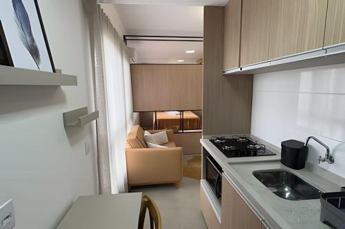 a small kitchen with a stove and a couch at Residencial Barin - Perto de TUDO! LZN Hospedagens in Santa Maria