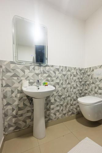 a bathroom with a sink and a toilet and a mirror at VILLA DE L'INTEGRATION in Ouagadougou