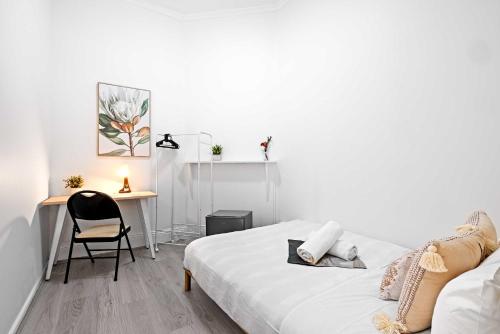 a white bedroom with a bed and a desk at No Frill Economic Double Room - Ideally Located - Shared External Bathroom & Kitchen in Sydney