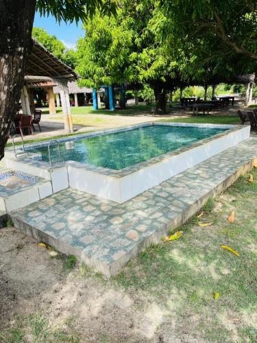 a swimming pool with a stone path around it at Chalé sítio Cumbe in Aracati