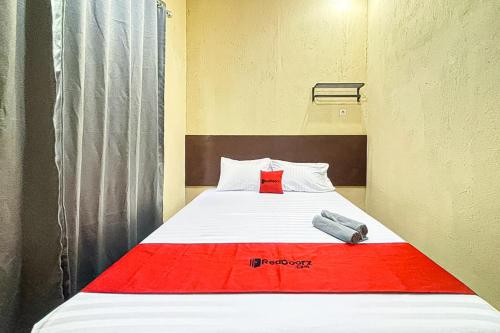 un lit dans une chambre avec une couverture rouge dessus dans l'établissement RedDoorz near RS Hermina Tangerang, 