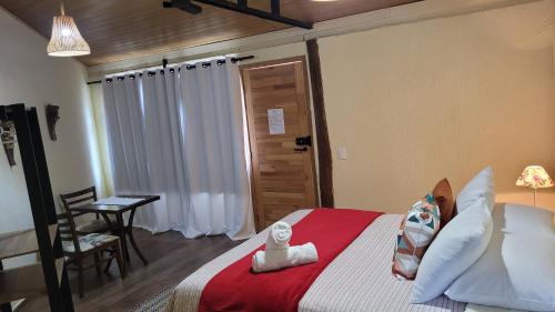 a bedroom with a bed and a table with a chair at Suítes La Reserve in Campos do Jordão