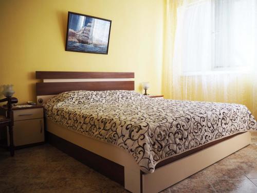 a bedroom with a bed with a comforter and a window at Guest House Konomaevi in Sozopol