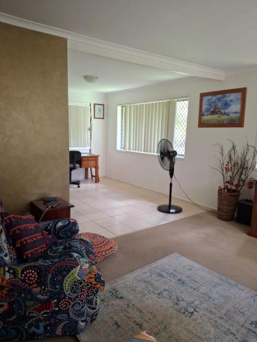 a living room with a couch and a fan at Sandi's Home in Gladstone